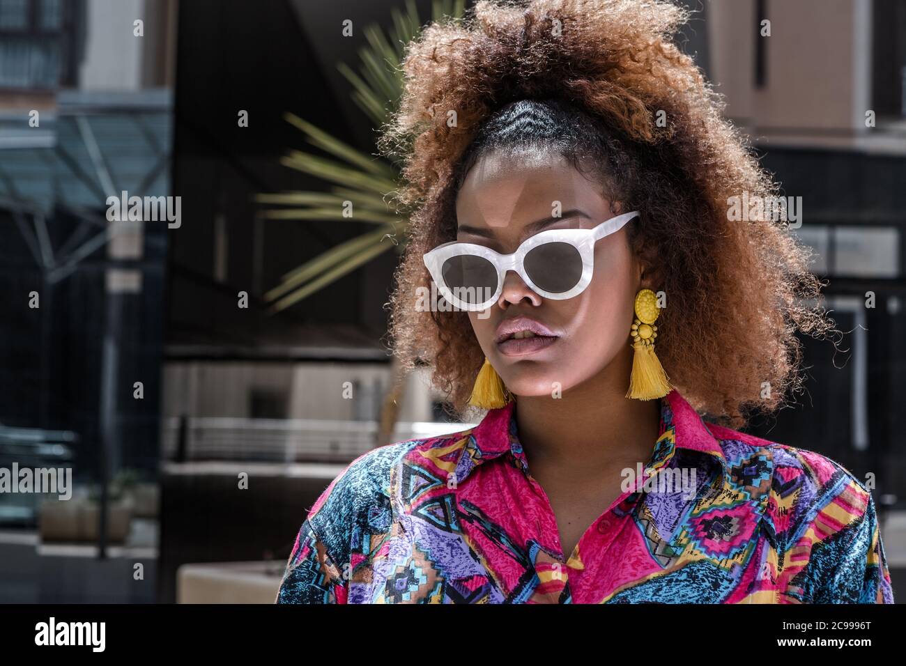 Contemporary confident young African American female with afro hair dressed  in bright colorful clothes with trendy accessories standing on city street  Stock Photo - Alamy