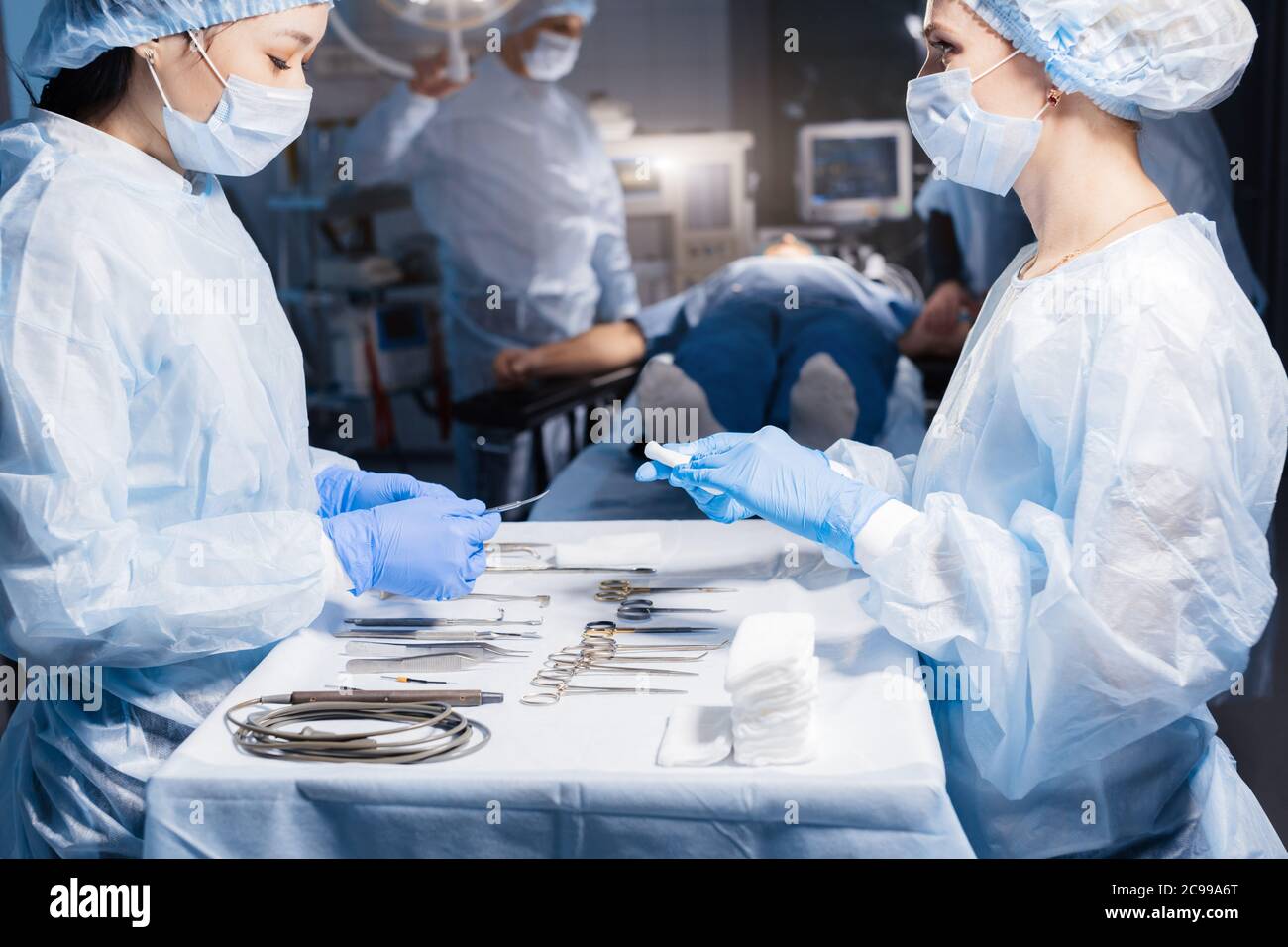 Nurse s hands holding surgical instruments and tools, close up including scalpels, forceps and tweezers arranged on a table. Surgeons at work in opera Stock Photo