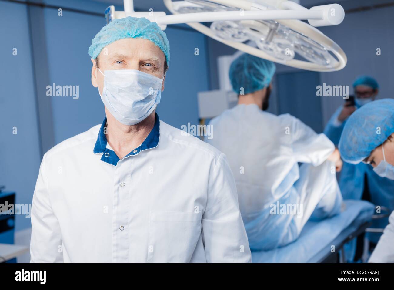 Portrait of senior doctor wearing medical protective mask and scrub cap