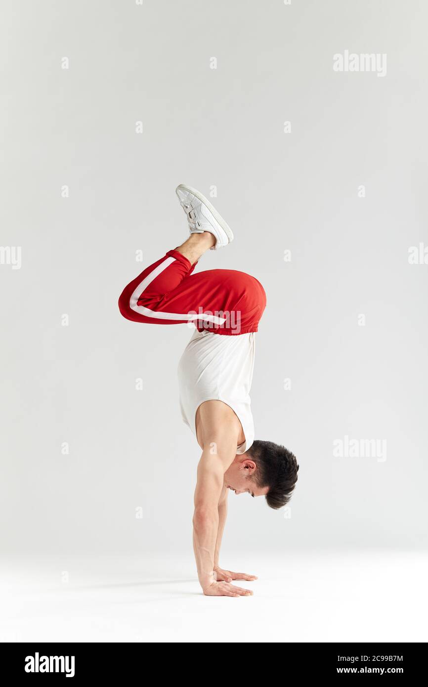 Male hip hop dancer or bboy freezes on vertical handstand with crossed legs , dancing isolated on white background Stock Photo