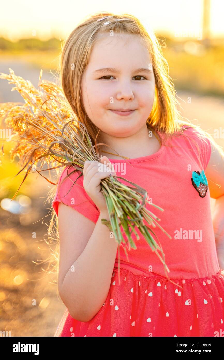 Cute smiling little girl in pink dress with bouquet of dried flowers in ...