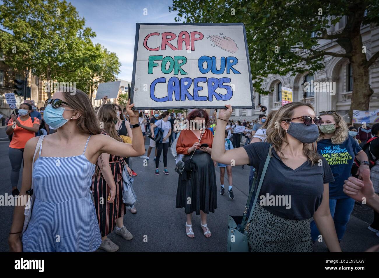 London, UK. 29th July, 2020. Coronavirus: NHS March for Pay Justice. Hundreds of NHS workers, key workers and supporters march from St. Thomas' Hospital to Downing Street gates demanding pay justice. The NHS workers demand they deserve a pay rise for the 20% pay cut since 2010 and have felt undervalued during the COVID-19 pandemic which saw masses of overtime, isolation from families and the loss of over 540 of workers to the virus. Credit: Guy Corbishley/Alamy Live News Stock Photo