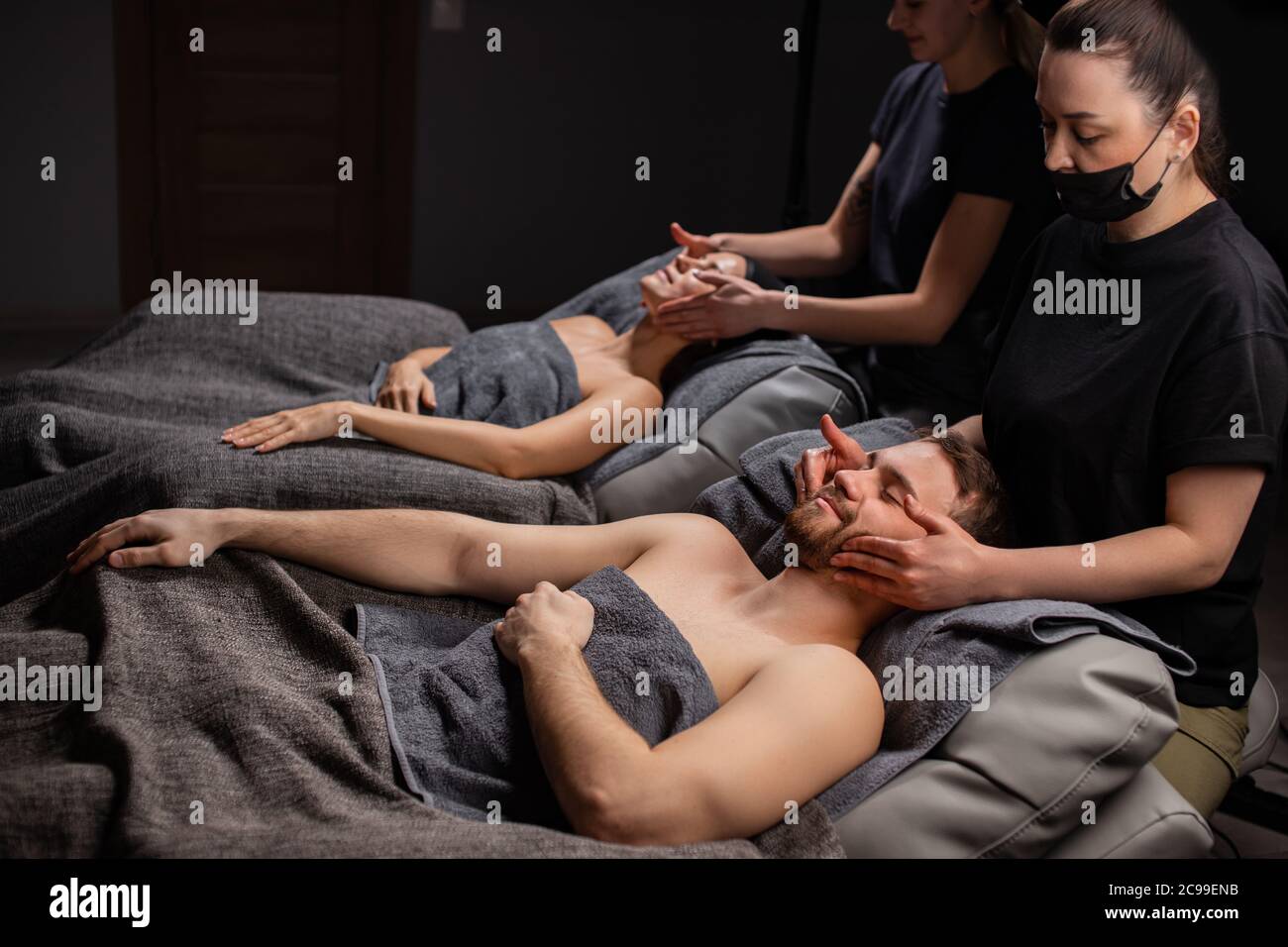 charming married couple enjoy a head massage in modern wellness spa salon. beauty treatment concept, healthy lifestyle, smooth skin concept Stock Photo