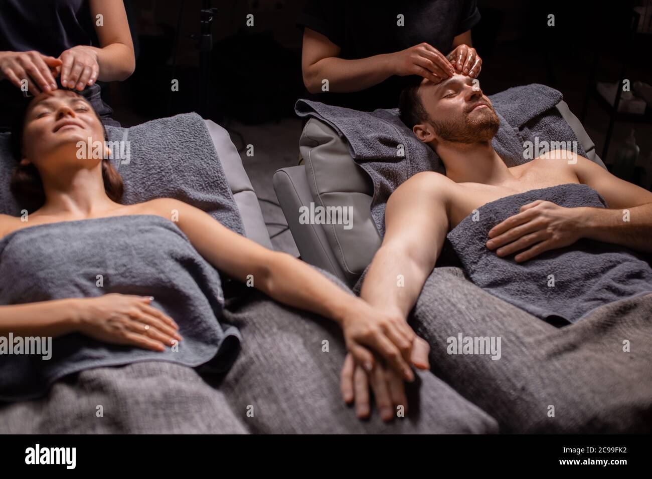 charming married couple enjoy a head massage in modern wellness spa salon. beauty treatment concept, healthy lifestyle, smooth skin concept Stock Photo
