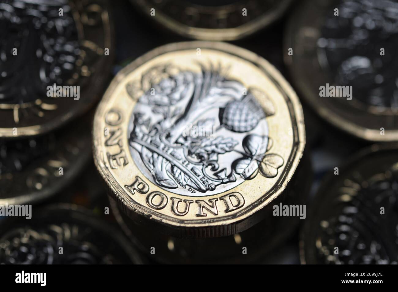 BRITISH ONE POUND COIN WITH MONEY RE THE ECONOMY RECESSION INCOME JOBS WAGES CORONAVIRUS ETC UK Stock Photo