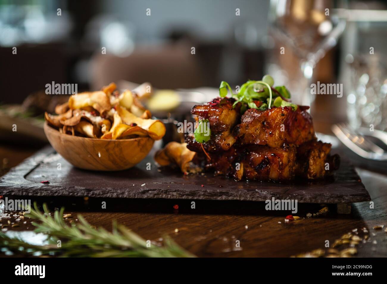 Pork ribs cooked at low temperature. Blackcurrant sauce, parsnip chips with Parmesan cheese. Delicious healthy meat food closeup served on a table for Stock Photo