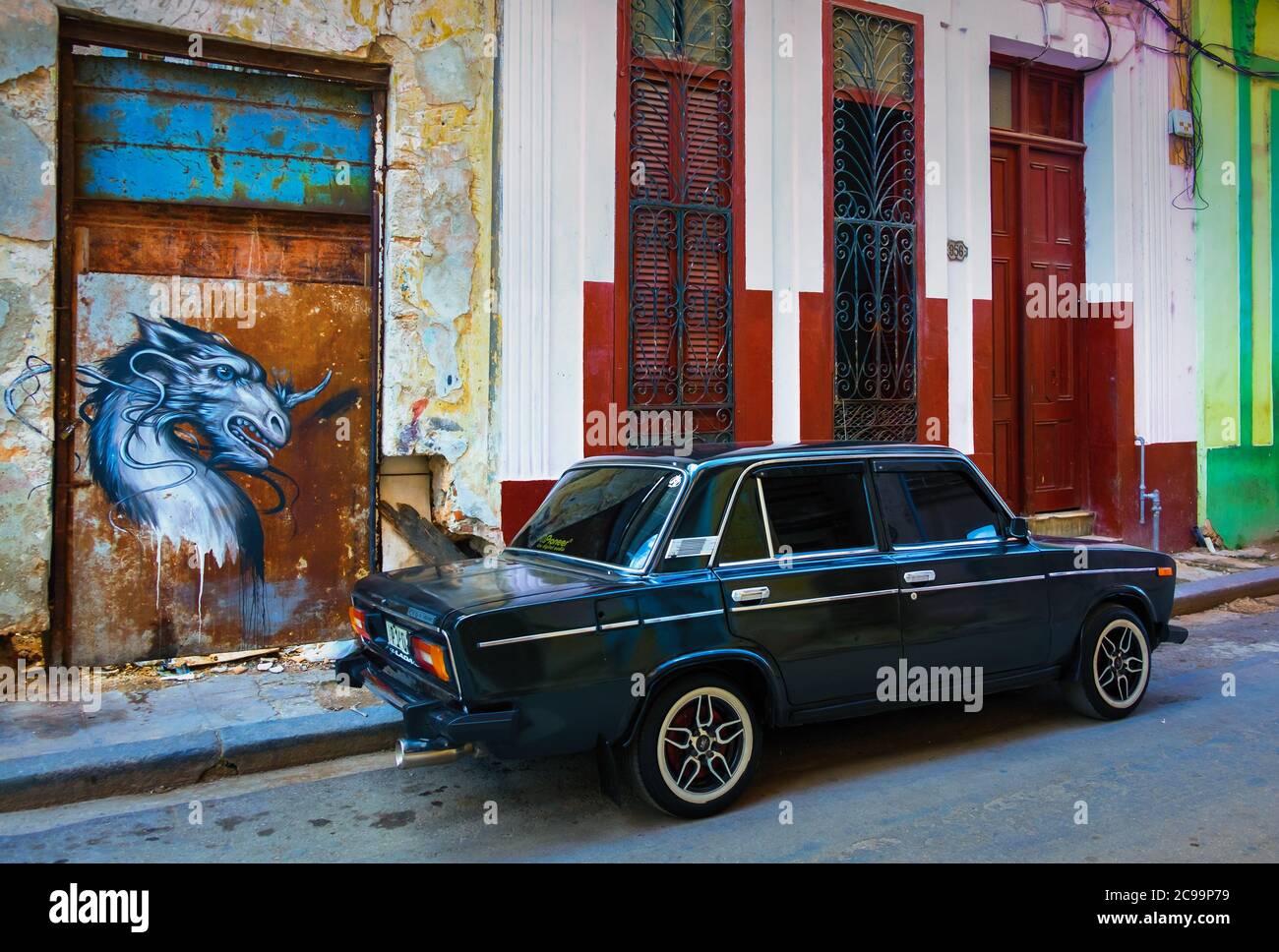 Havana, Cuba, July 2019, black Lada 1600 car parked in front of graffiti represented a chimera in the oldest part of the capital Stock Photo