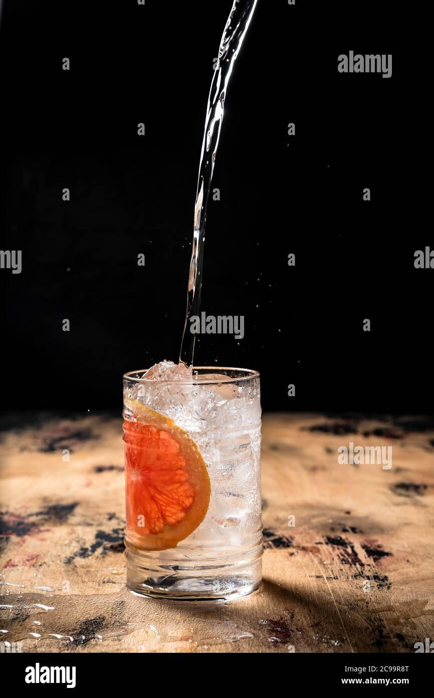 Gin and tonic cocktail recipe, pouring tonic into a highball glass