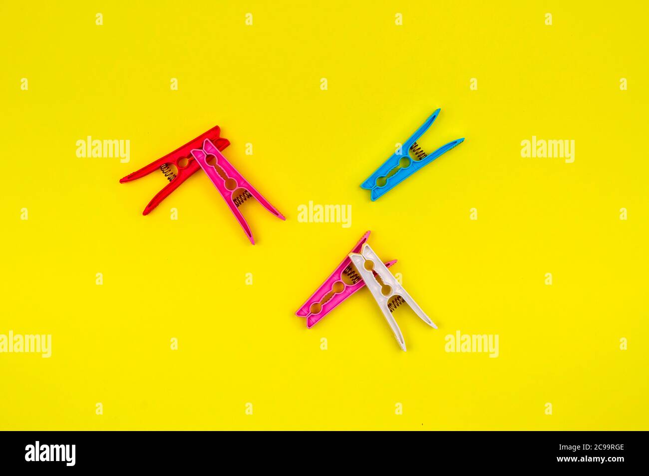 Multi-colored clothes pins on a yellow background. Stock Photo