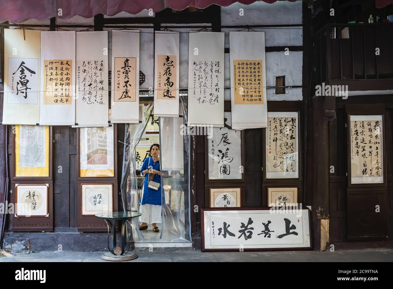 Chongqing, China - August 2019 : Woman purchasing products inside the small calligraphy shop in Ci Qi Kou Ancient town Stock Photo