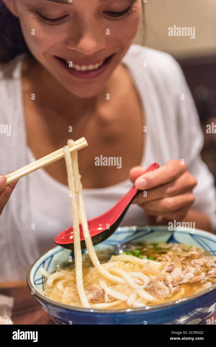 Ramen noodles girl eating soup bowl at japanesese restaurant at night. City travel lifestyle. Stock Photo