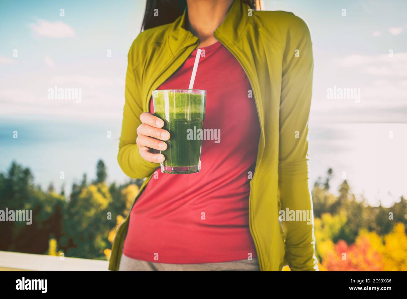 Green smoothie breakfast detox diet food cleanse juice drink. Woman eating healthy for weight loss, morning meal outside in autumn nature. Stock Photo