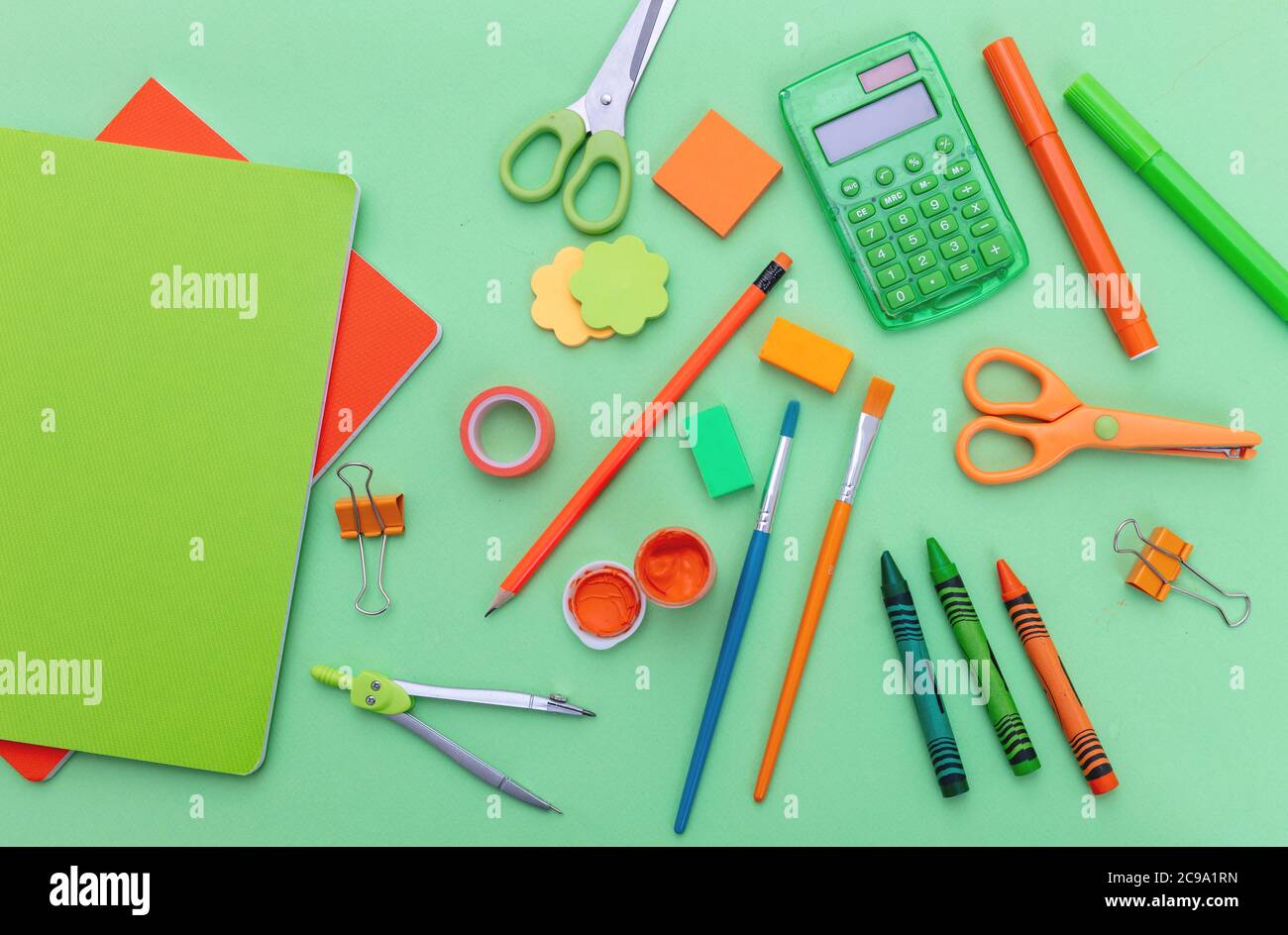 School supplies flat lay. Stationery on green color background, top