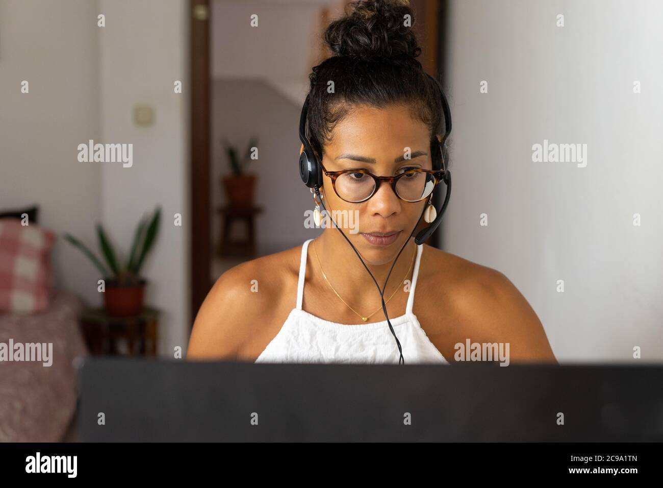 Working brazilian young woman in bedroom. Telemeeting. Video conference. Remote work. Call center home. Stock Photo