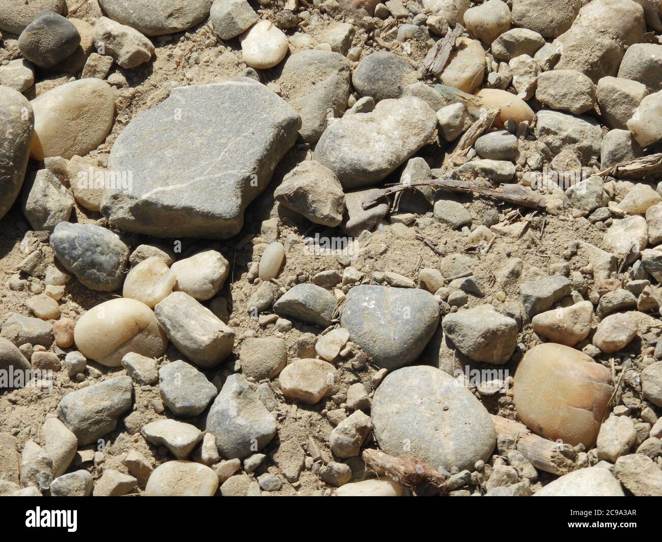 Top view of different shaped and sized rocks on a dirt floor Stock Photo