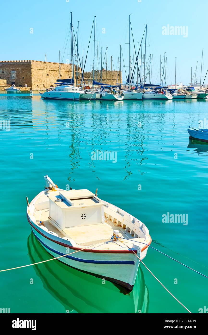 Small white fishing boat in the harbour near Koules Fortress in Heraklion, Crete, Greece. Greek scenery Stock Photo
