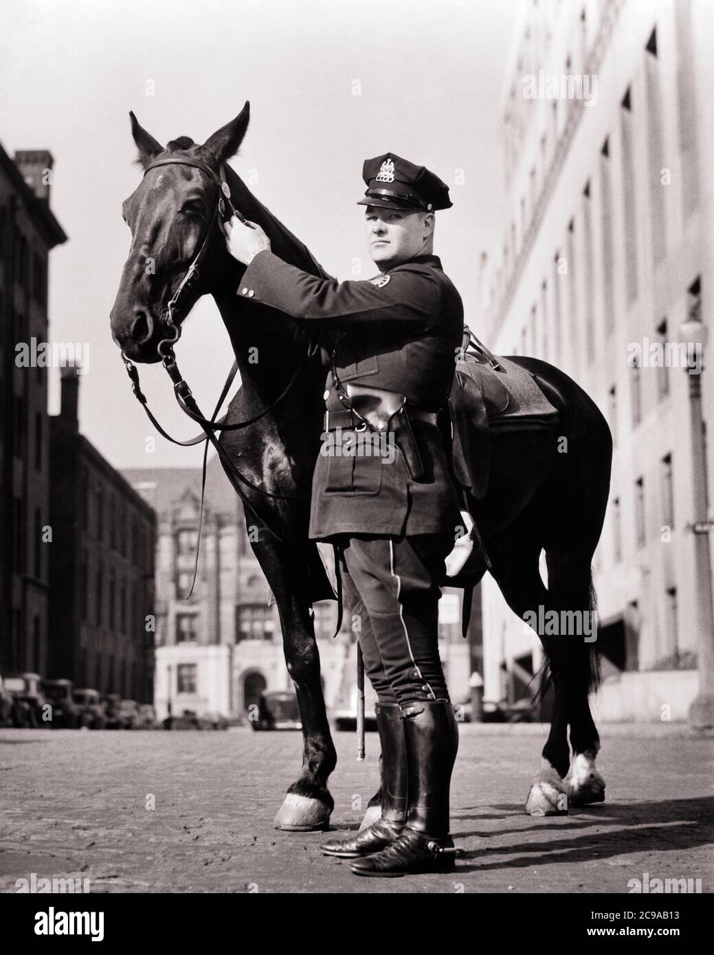 1930s 1940s UNIFORMED MOUNTED POLICEMAN STANDING NEXT TO HIS HORSE LOOKING  AT CAMERA ST. LOUIS MISSOURI USA - c1097 HAR001 HARS PERSONS UNITED STATES  OF AMERICA CARING MALES ORDER OFFICER CONFIDENCE NEXT