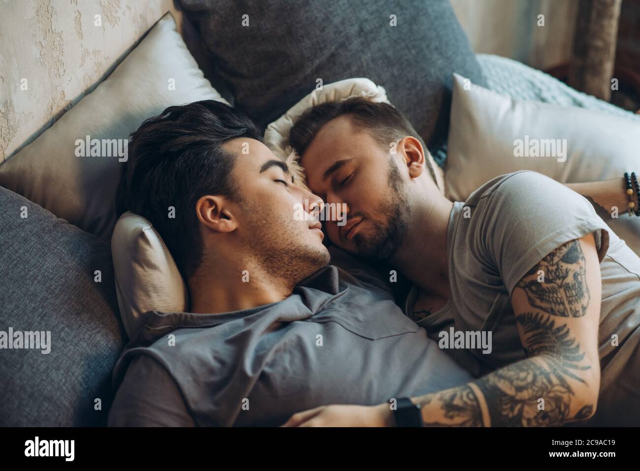 Young sweet couple have same-sex romance, embracing in bed kissing, passionate active man catches his boyfriend in caddle, honeymoon, LGBT concept Stock Photo photo