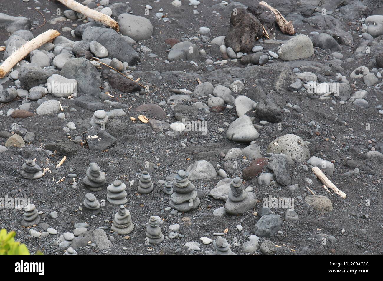 A group of small cairns, rock totems, on the black sandy shore of Oheo Gulch in the Kipahulu District in Maui, Hawaii, USA Stock Photo