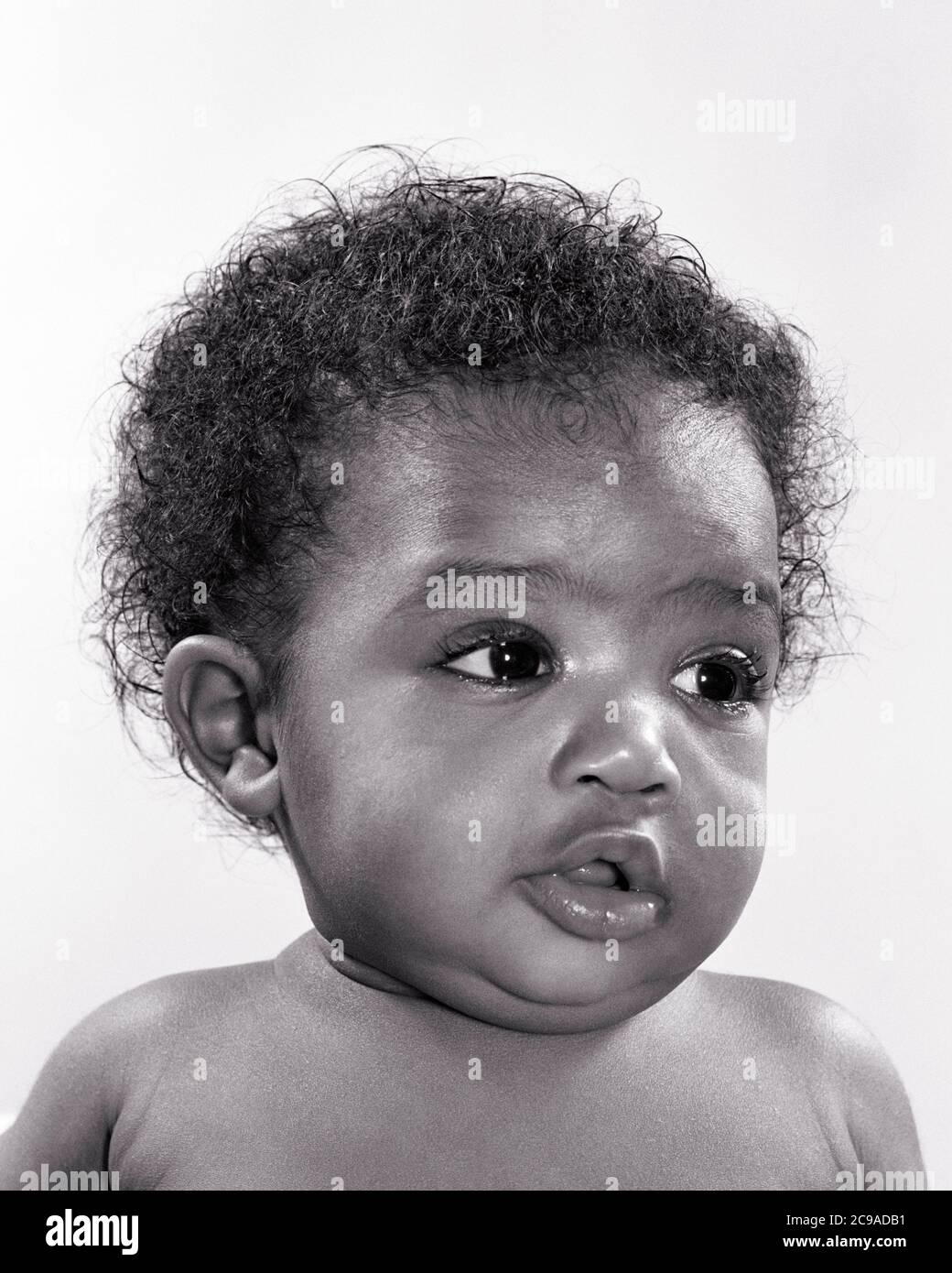 1940s 1950s PORTRAIT CHARMING CUTE WIDE-EYED AFRICAN-AMERICAN BABY GIRL SITTING UPRIGHT LOOKING TO SIDE - n599 HAR001 HARS JUVENILES ATTENTIVE BABY GIRL BLACK AND WHITE HAR001 OLD FASHIONED AFRICAN AMERICANS Stock Photo