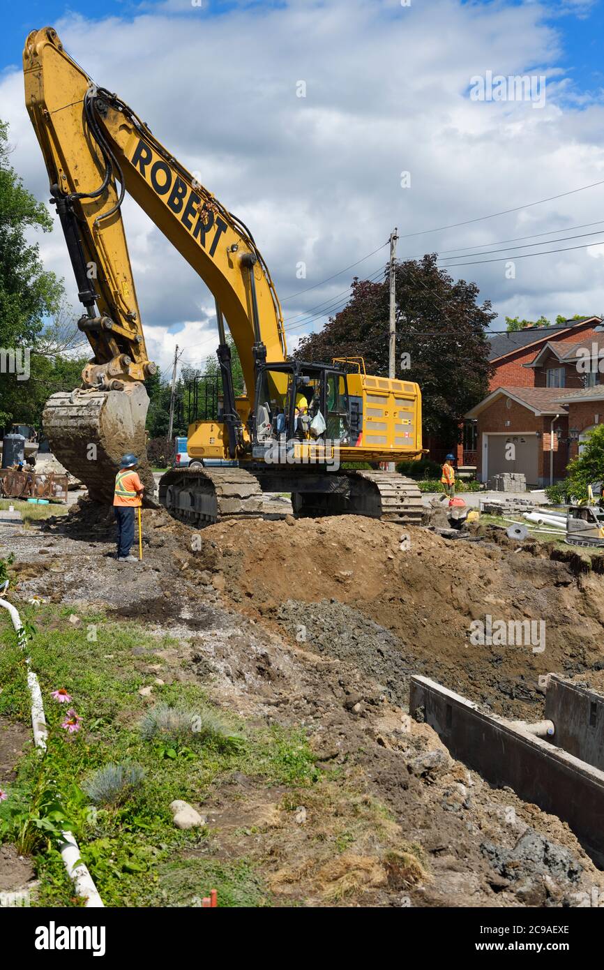 Excavator digging up a trench for new sewer installation in a street in ...