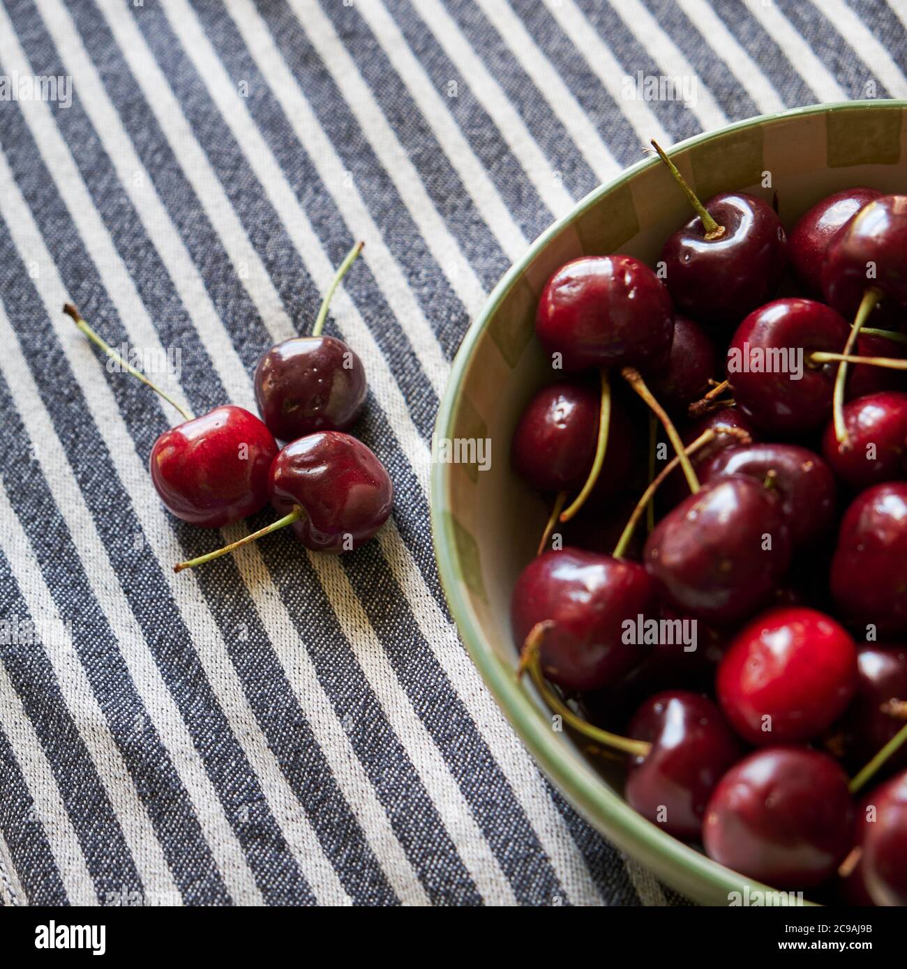 Fresh dark red cherries in a bowl. The fresh fruit are long stem cherries. Stock Photo