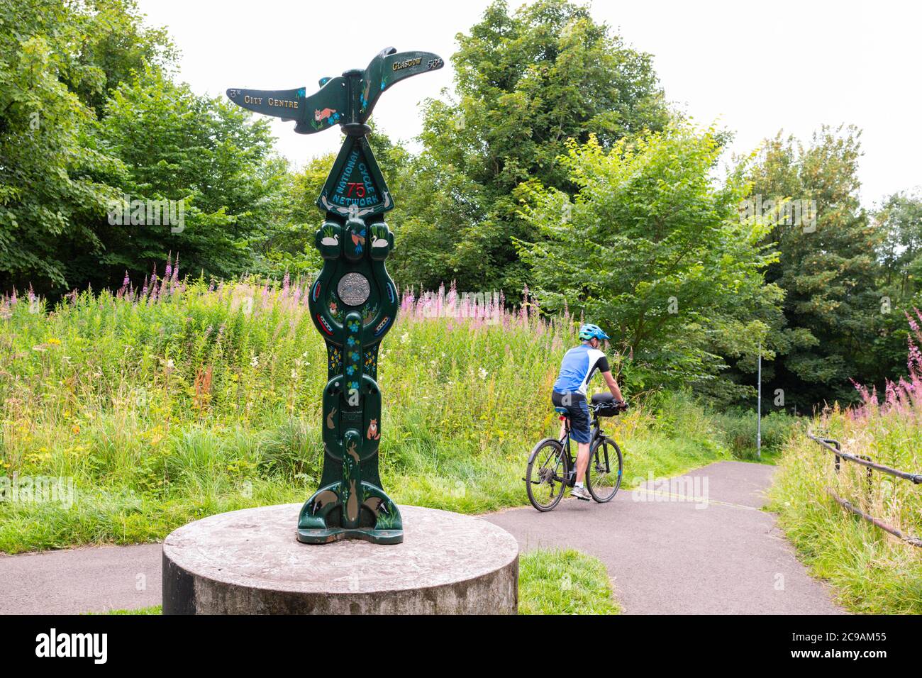 cyclist on ebike  passing Millennium Milepost on National Cycle Network 75, a sustrans cycle route - Kingsknowe, Edinburgh, Scotland, UK Stock Photo