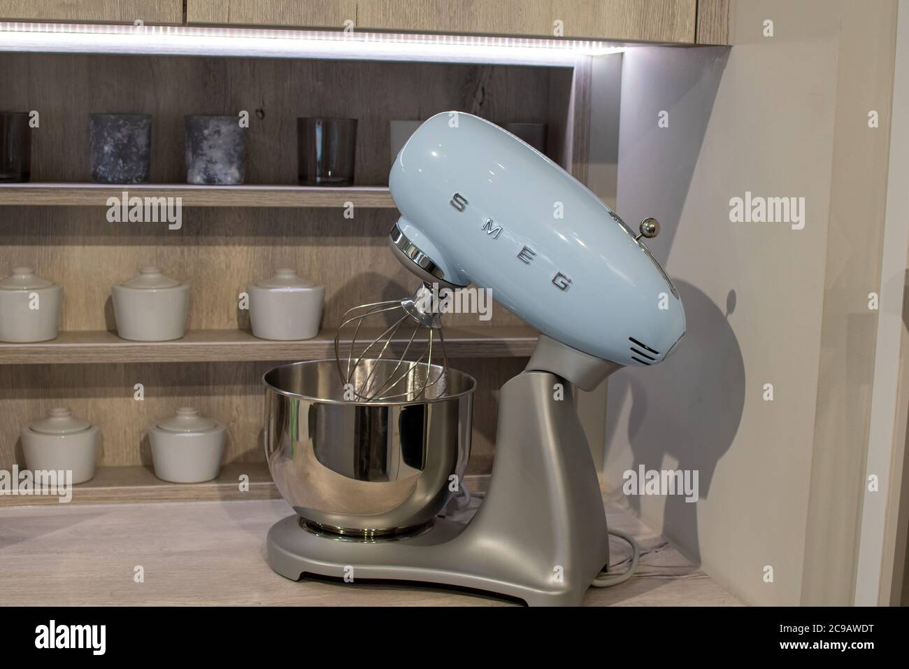Smeg food mixer and bowl standing in front of kitchen shelves with jars