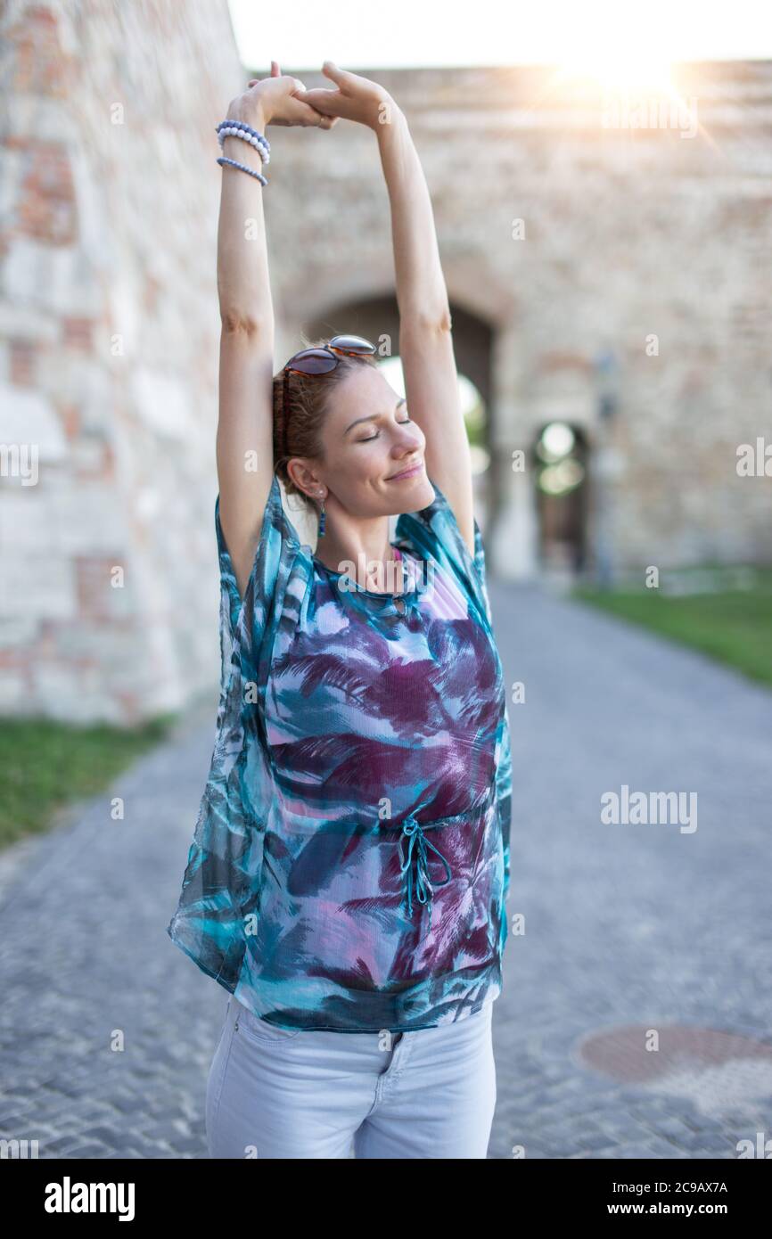 Young caucasian urban woman stretching in sunrise Stock Photo