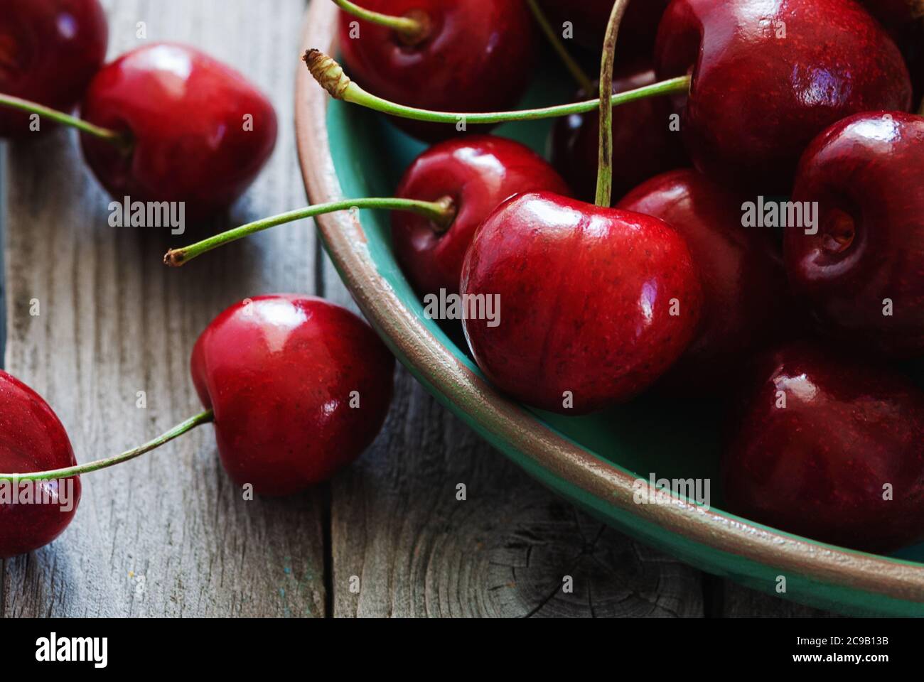 cherries in a bowl on wooden table closeup Stock Photo