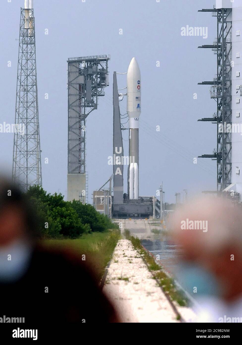 July 29, 2020 - Cape Canaveral, Florida, United States - Members of the media wearing protective face masks walk near an Atlas V rocket with NASA's Perseverance rover as it stands ready for launch tomorrow morning at pad 41 at Cape Canaveral Air Force Station on July 29, 2020 in Cape Canaveral, Florida. As the key component of the Mars 2020 mission, Perseverance is scheduled to land on the Red Planet in February 2021 where it will seek signs of ancient life and collect rock and soil samples for possible return to Earth. (Paul Hennessy/Alamy Live News) Stock Photo