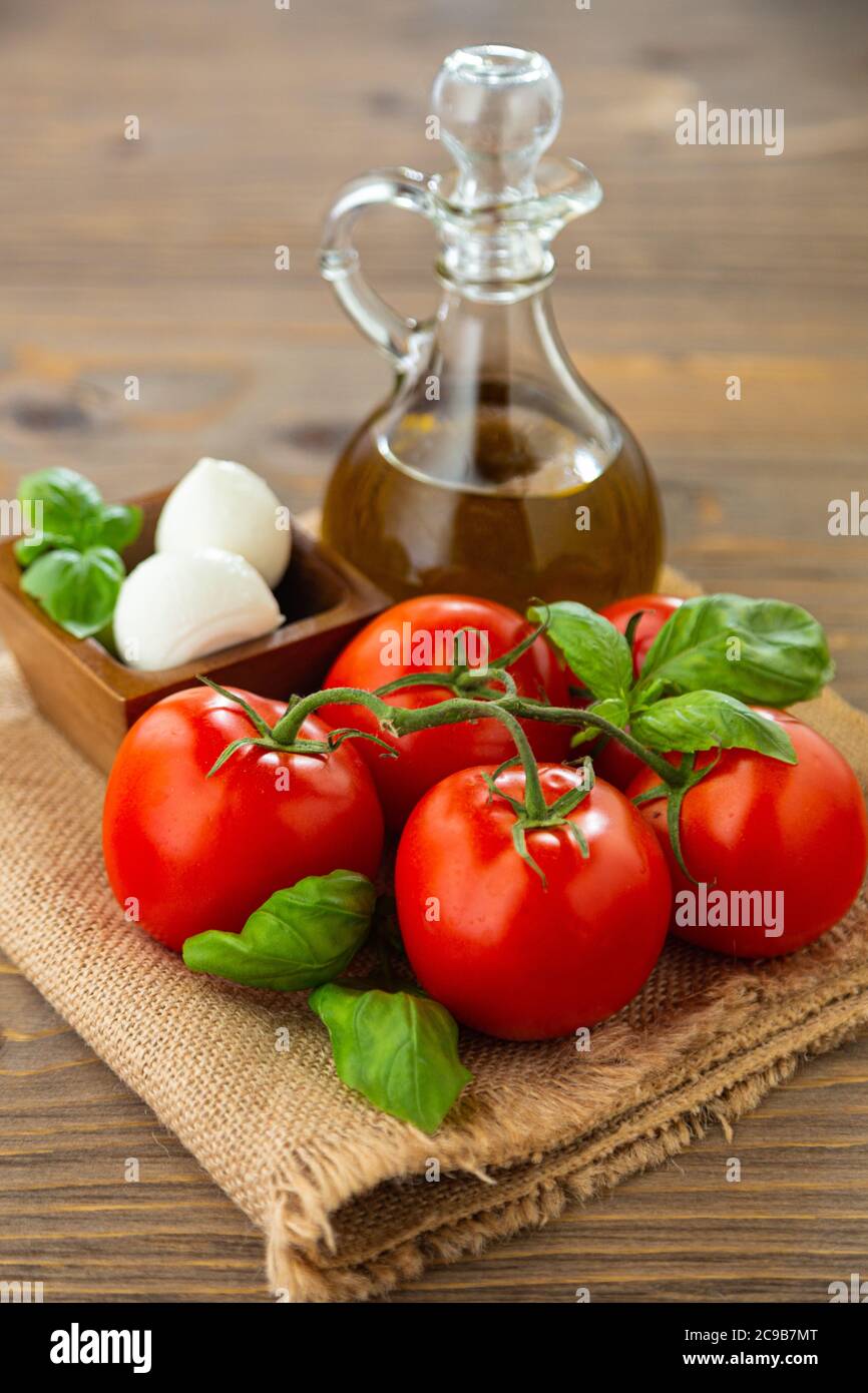Ingredients for Caprese Salad on a burlap napkin against a dark wood background. Stock Photo