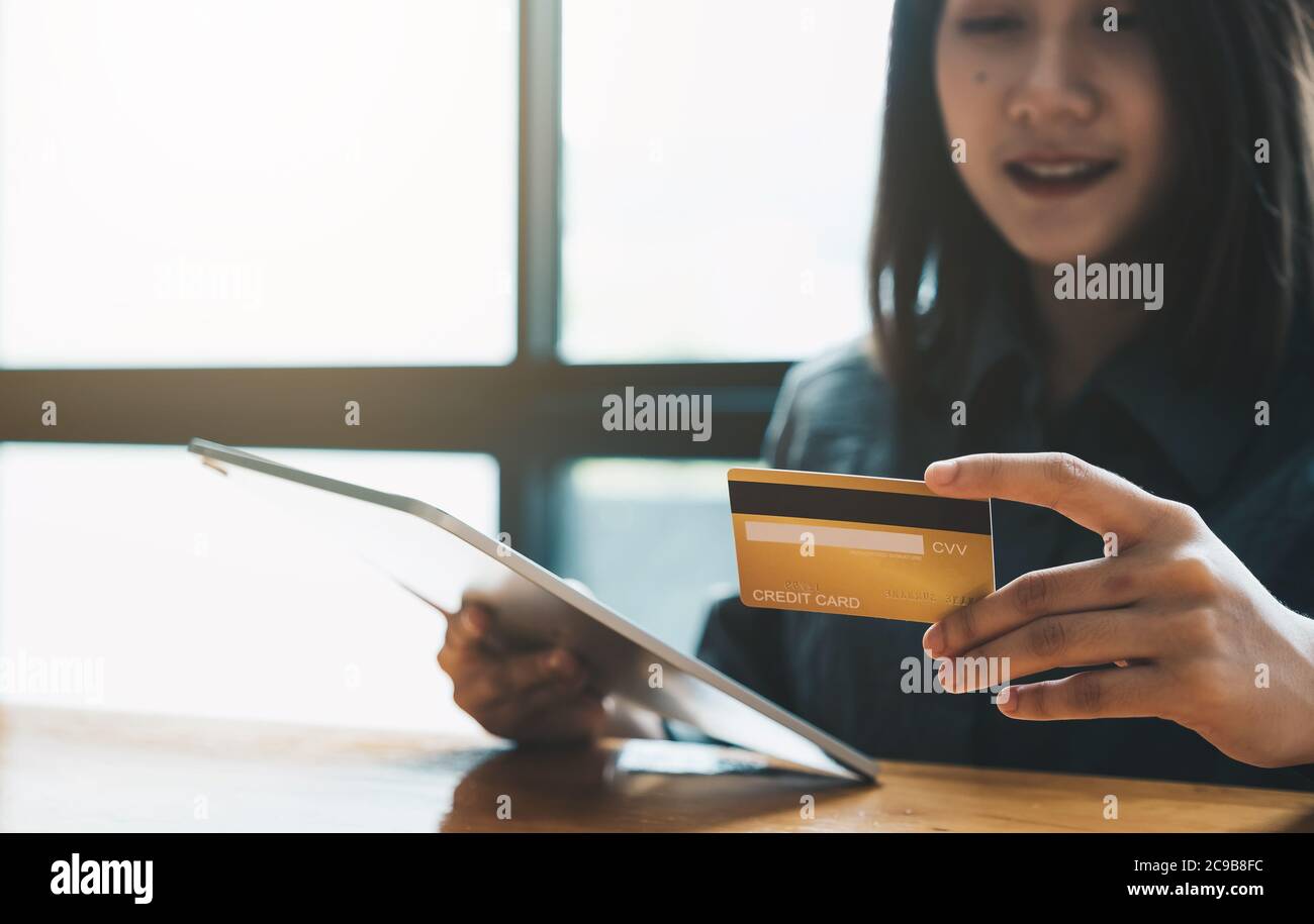 Young woman holding credit card and using tablet computer. Online shopping concept Stock Photo