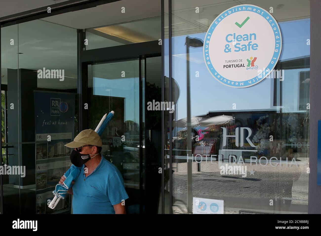 Algarve, Portugal. 29th July, 2020. A Tourist wearing a facial mask leaves a Hotel with the 'Clean and Safe' stamp in Portimao, Algarve region, Portugal on July 29, 2020. Considering the widespread concern in the resumption of economic and social activity, Turismo de Portugal created a 'Clean and Safe' stamp of approval to distinguish tourist activities which are compliant with hygiene and cleaning requirements for the prevention and control of COVID-19 and other possible infections. Credit: Pedro Fiuza/ZUMA Wire/Alamy Live News Stock Photo