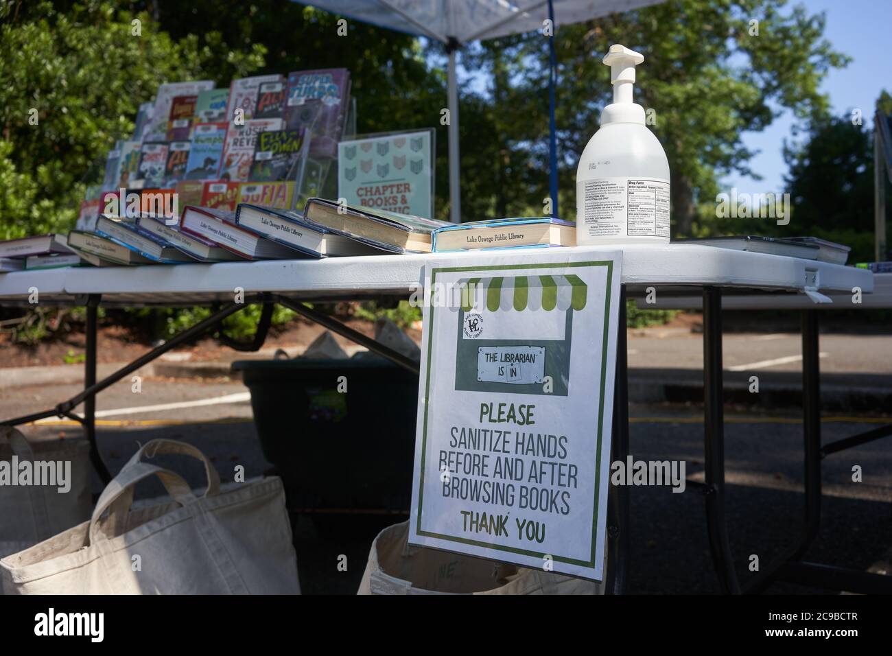 Signs at Lake Oswego's outdoor library remind readers to sanitize hands before and after browsing books to prevent the spread of the coronavirus. Stock Photo