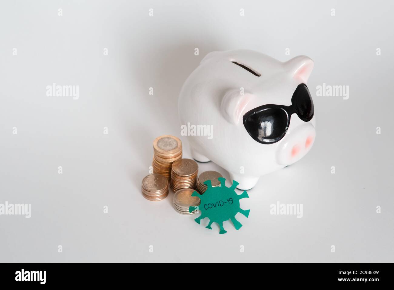 danger to financial savings due to a pandemic virus. piggy bank in a mask on a white background. coins Stock Photo