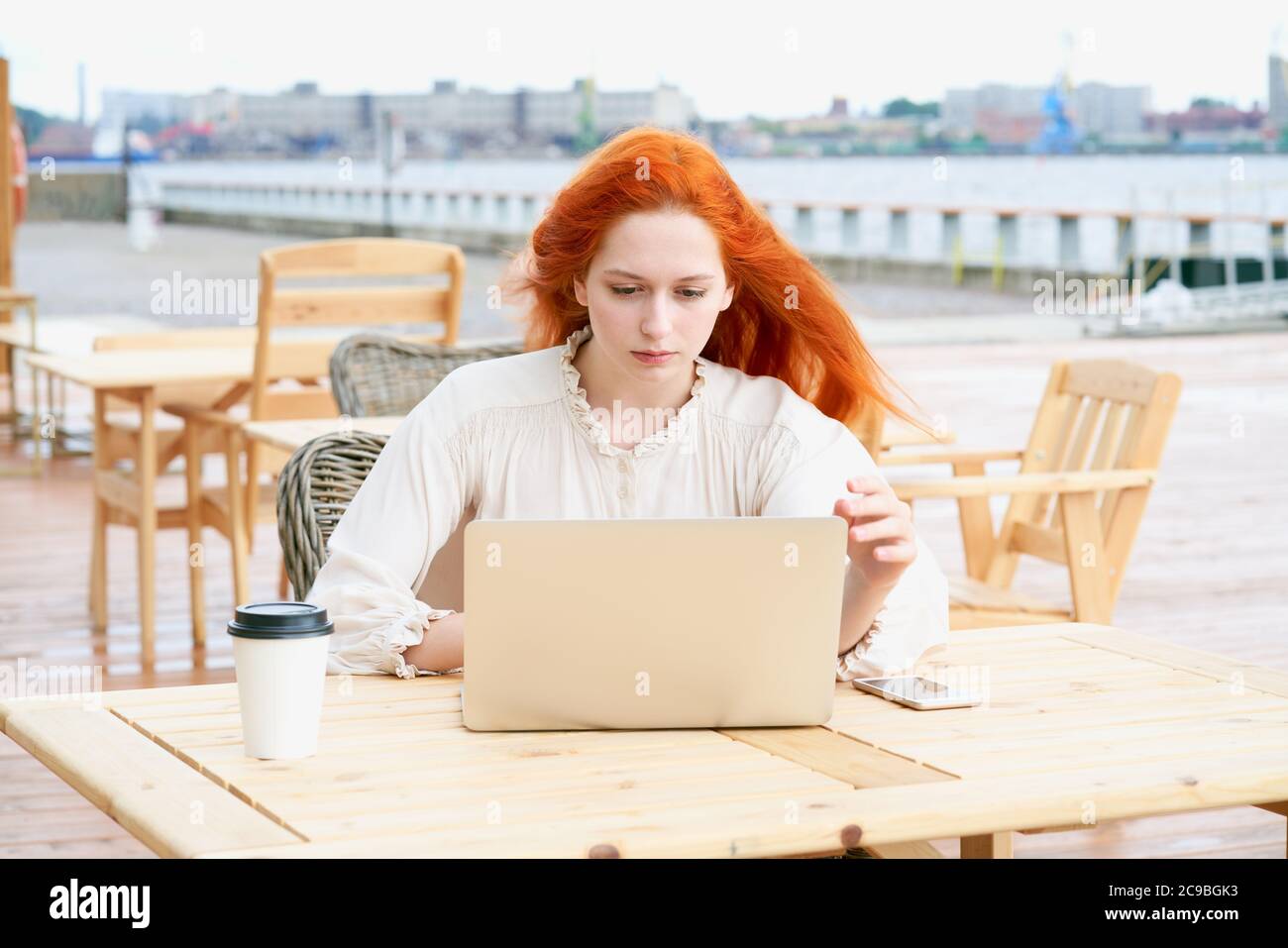 Redhead female looking at laptop in cafe outside Stock Photo - Alamy