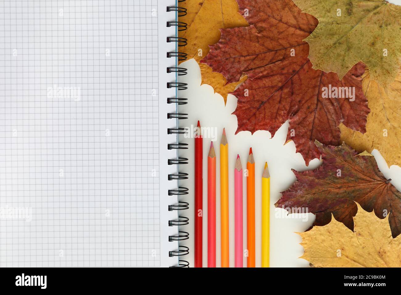 On the table are colored pencils and a notebook Stock Photo