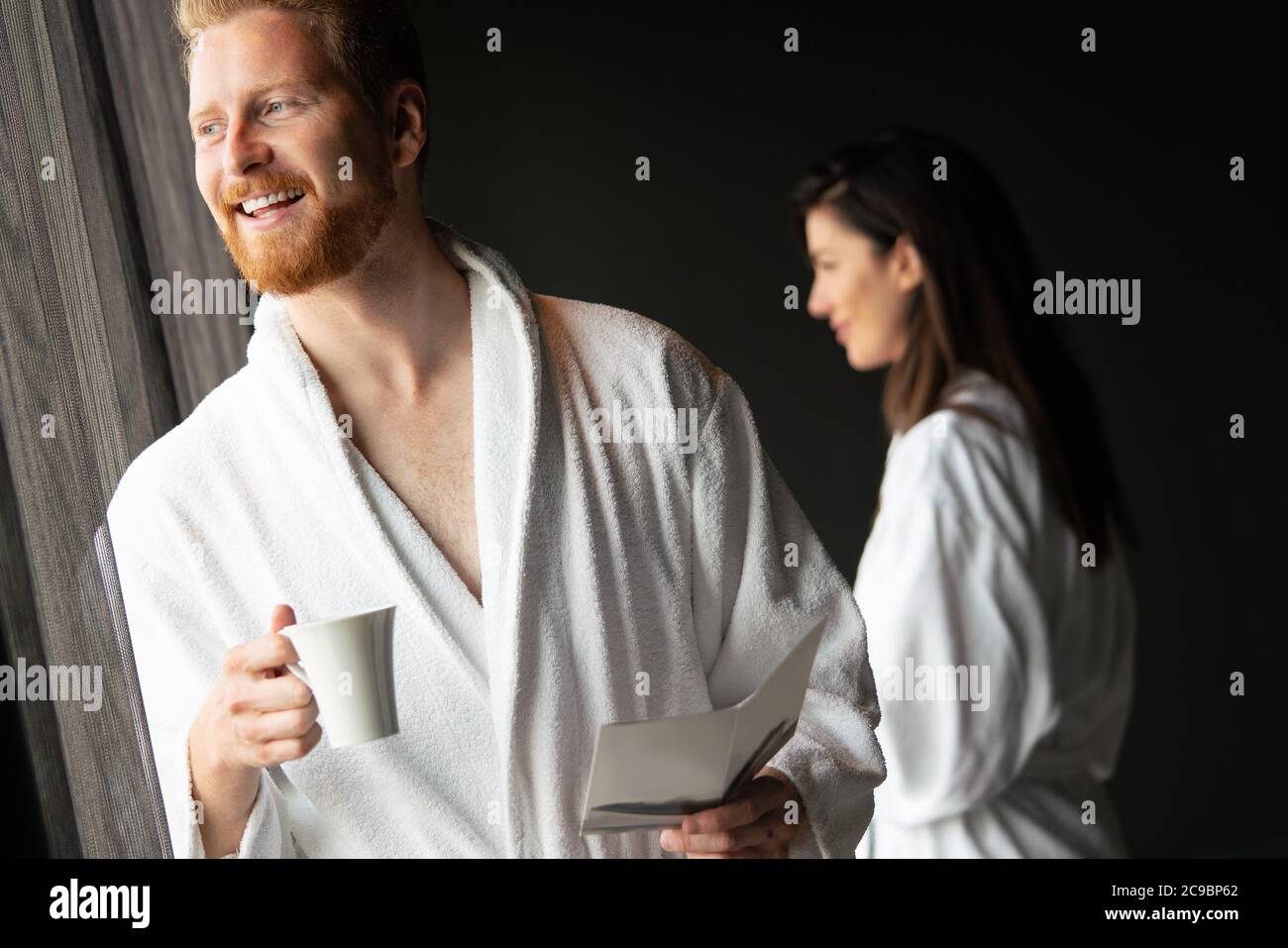 Young man in bathrobe drinking coffee at home Stock Photo
