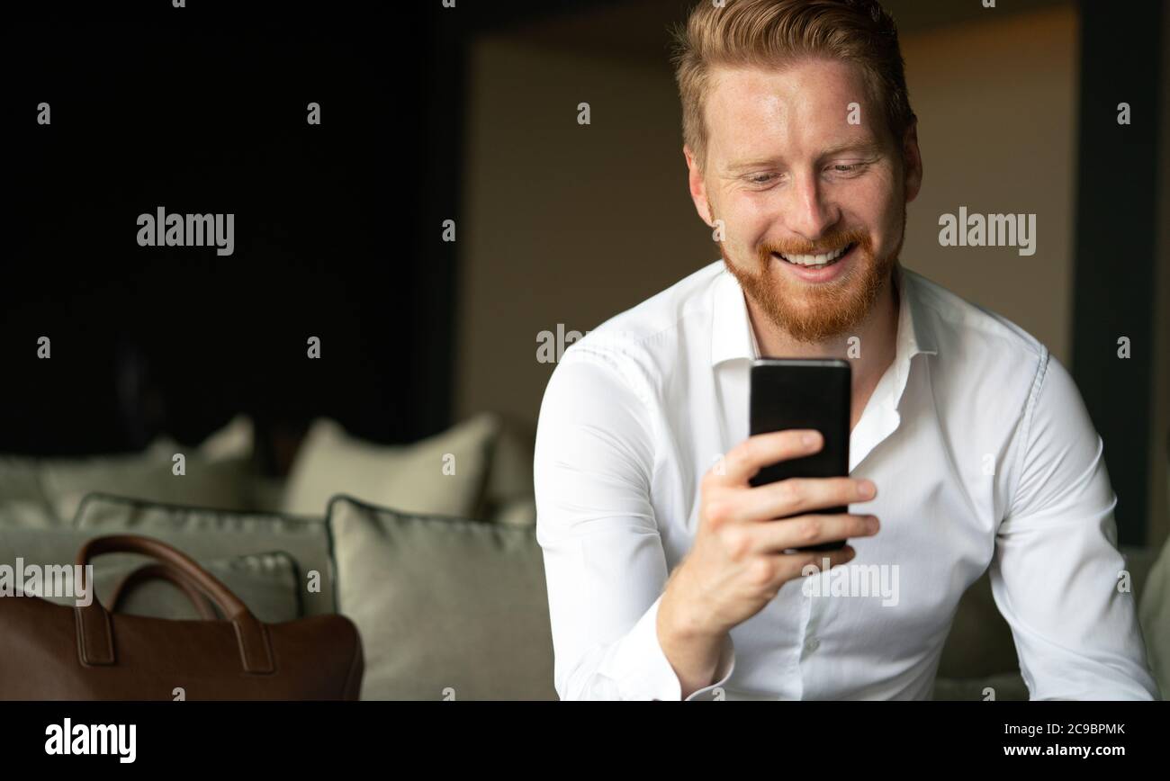 Happy young man using his smart phone at office Stock Photo