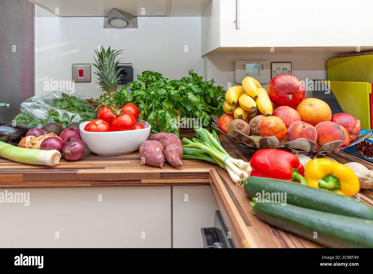 Abundance of fresh vegetables and fruits on kitchen worktop. Stock Photo