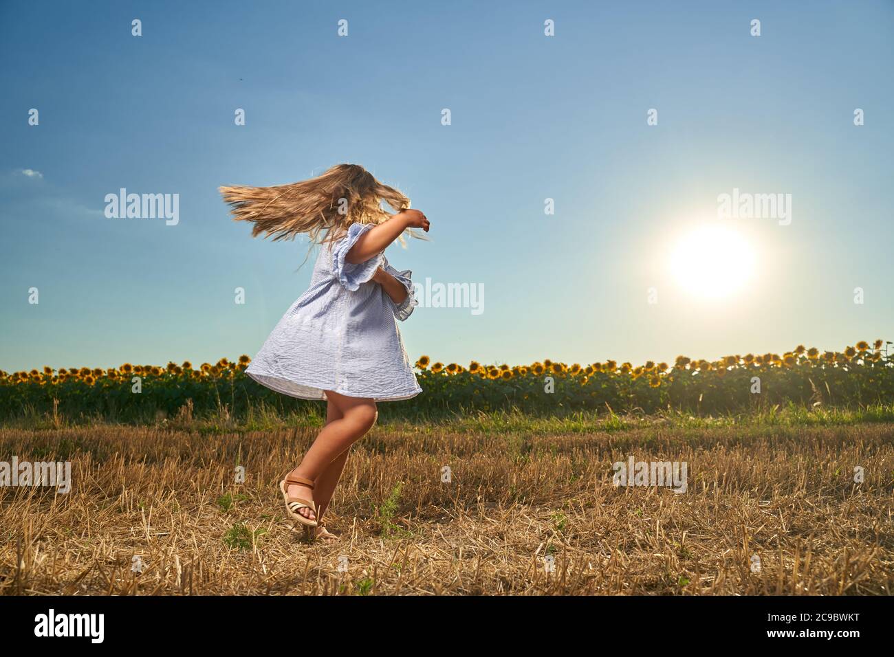 Happy little girl dancing in front of a sunflower field Stock Photo - Alamy