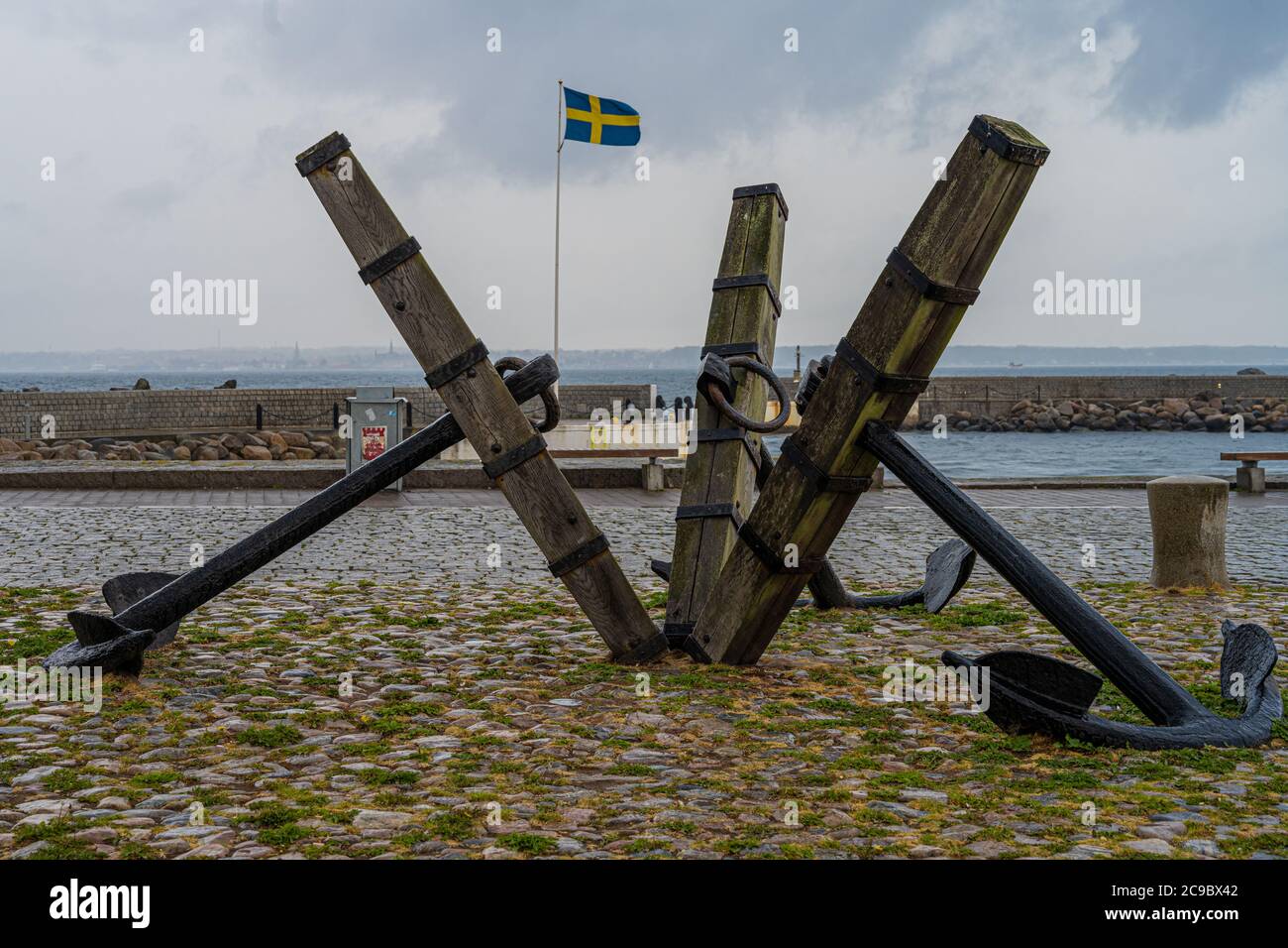 Three old anchors at Parapeten in Helsingborg, Sweden. This area has a long and close relationship with maritime activity. Swedish flag in the background Stock Photo