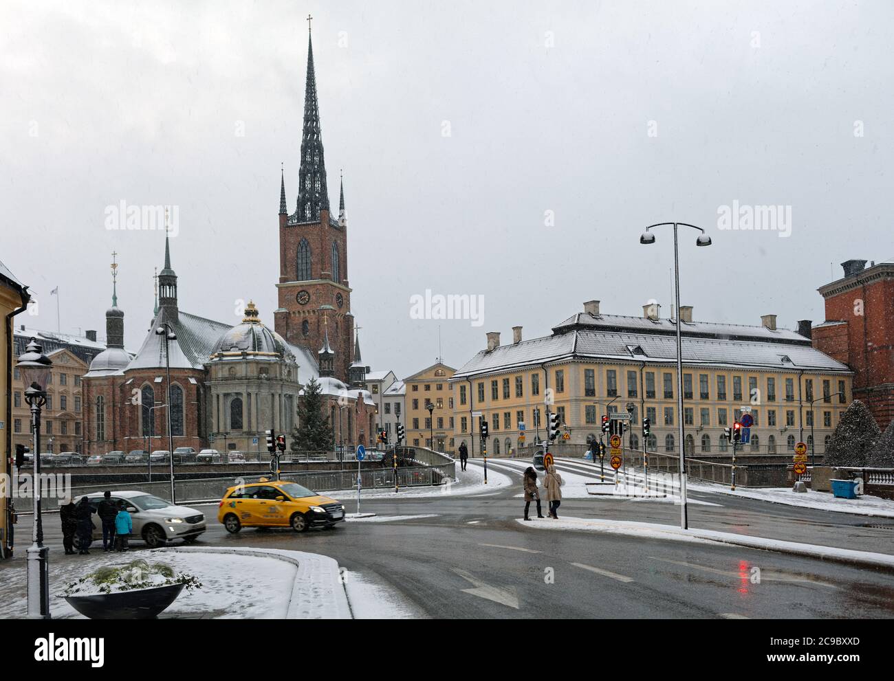 People at the crossroad at Riddarholmsbron bridge against the Riddarholmen Church in Gamla Stan, the historical center of Stockholm, Sweden Stock Photo