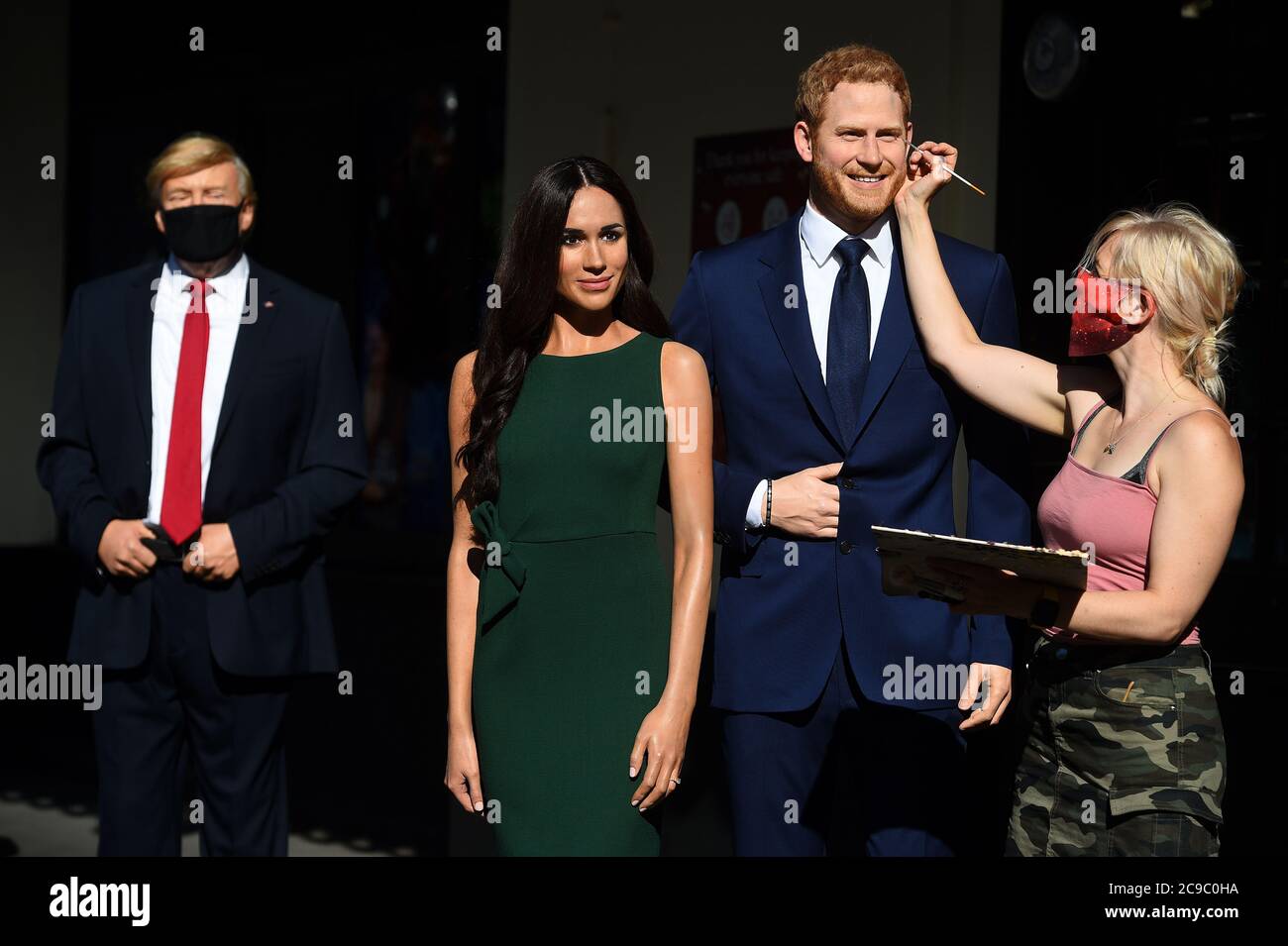 An artist puts the finishing touches the wax figures of the Duke and Duchess of Sussex, in the entrance line at Madame Tussaud's in London, as the attraction prepares to reopen to the public following the easing of lockdown restrictions in England. Stock Photo