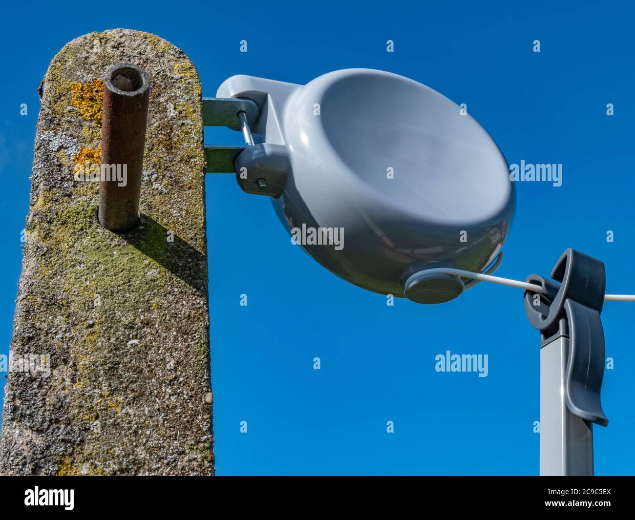 Retractable washing line reel (with branding removed) attached to a  concrete post, with blue sky. A washing pole is hanging on the line ready  for use Stock Photo - Alamy
