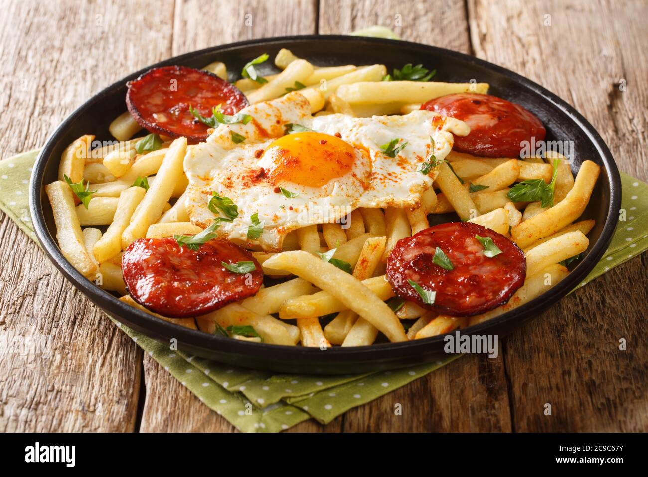 Delicious food fried egg with French fries and chorizo close-up in a plate on the table. horizontal Stock Photo