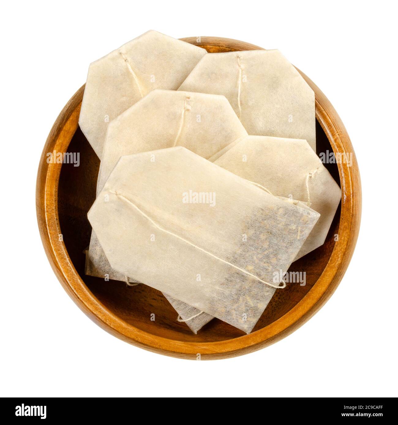 Tea bags in wooden bowl. Small, porous, sealed bag, made of filter paper, with string, containing shredded tea, to put into water and make an infusion. Stock Photo
