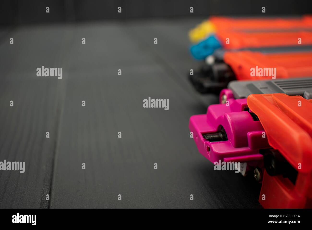New toner cartridges for laser printer in magenta, black, yellow and cyan colors, close-up, on gray wooden background Stock Photo