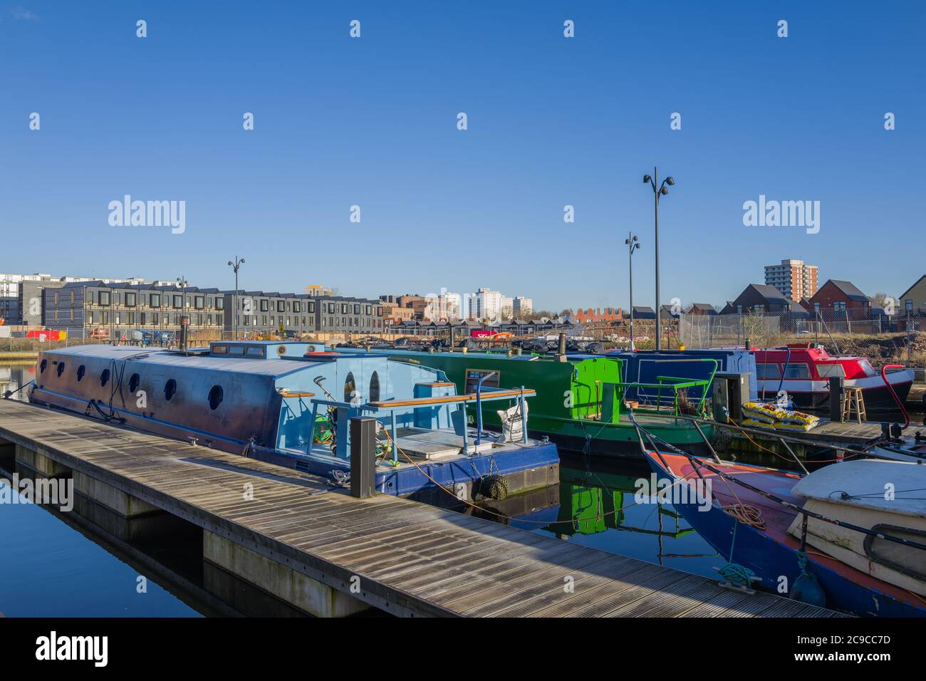 City living - canal boats on New Islington Marina. Photo features development of townhouses by Urban Splash. All council tower blocks on the horizon. Stock Photo